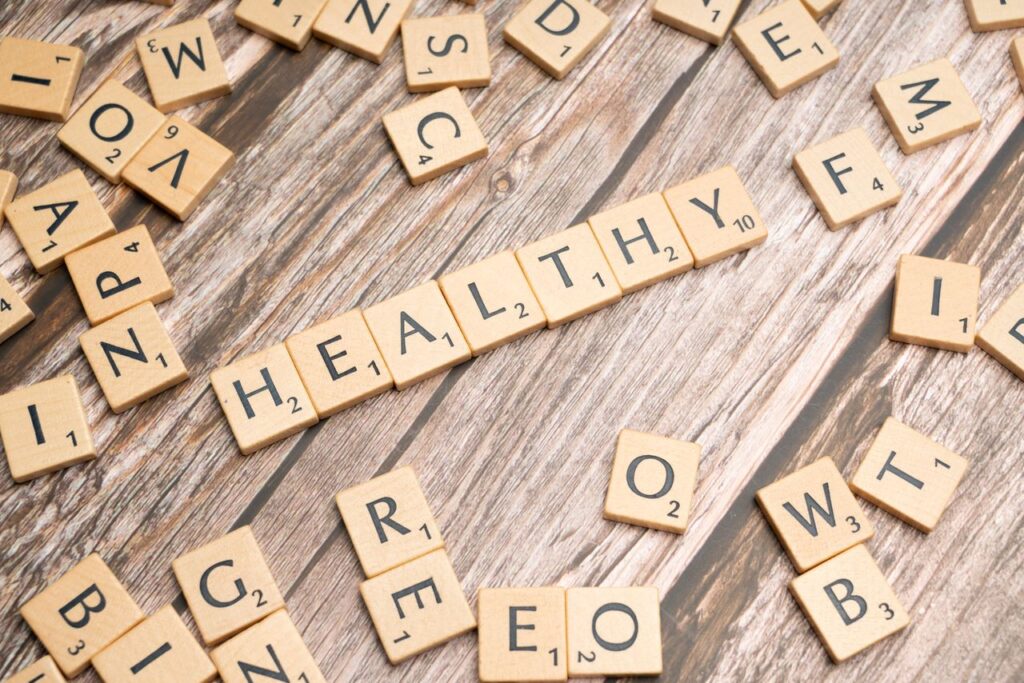 Wooden letter tiles arranged on a wooden surface spelling out 'healthy', symbolizing wellness.