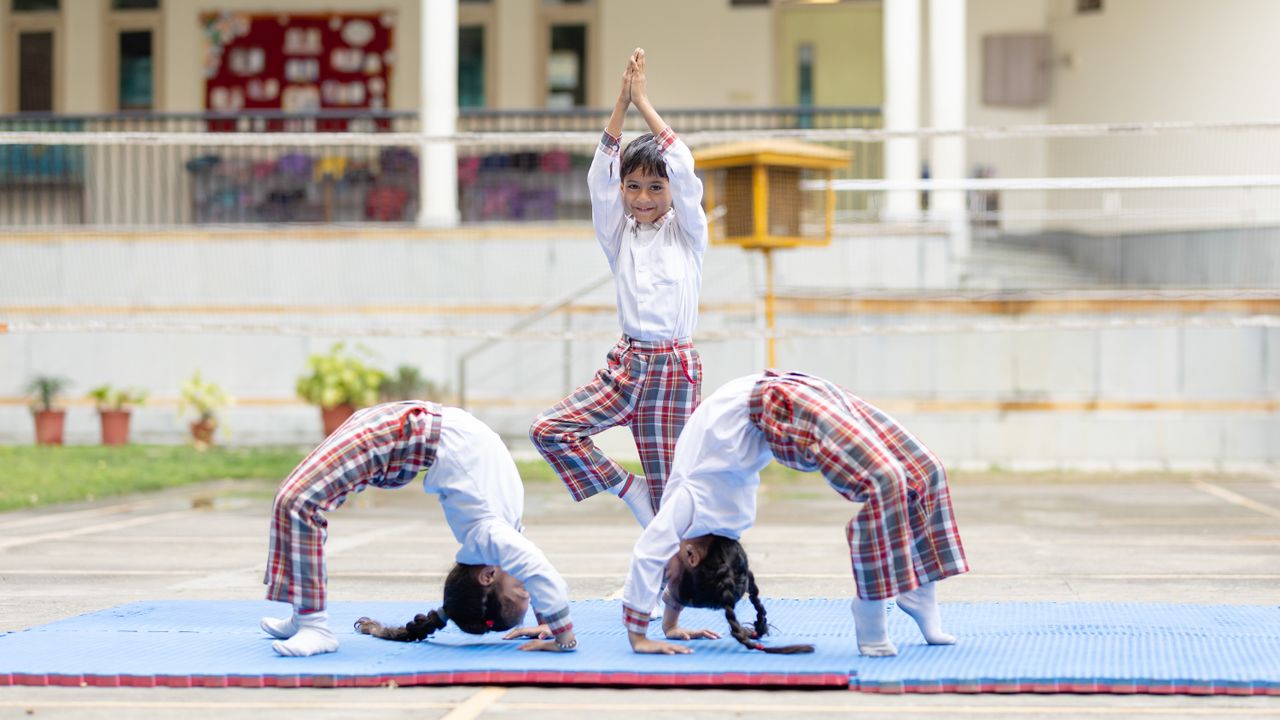 Mastering the First Impression: Your intriguing post title goes here Three children performing yoga poses outdoors on a school playground.