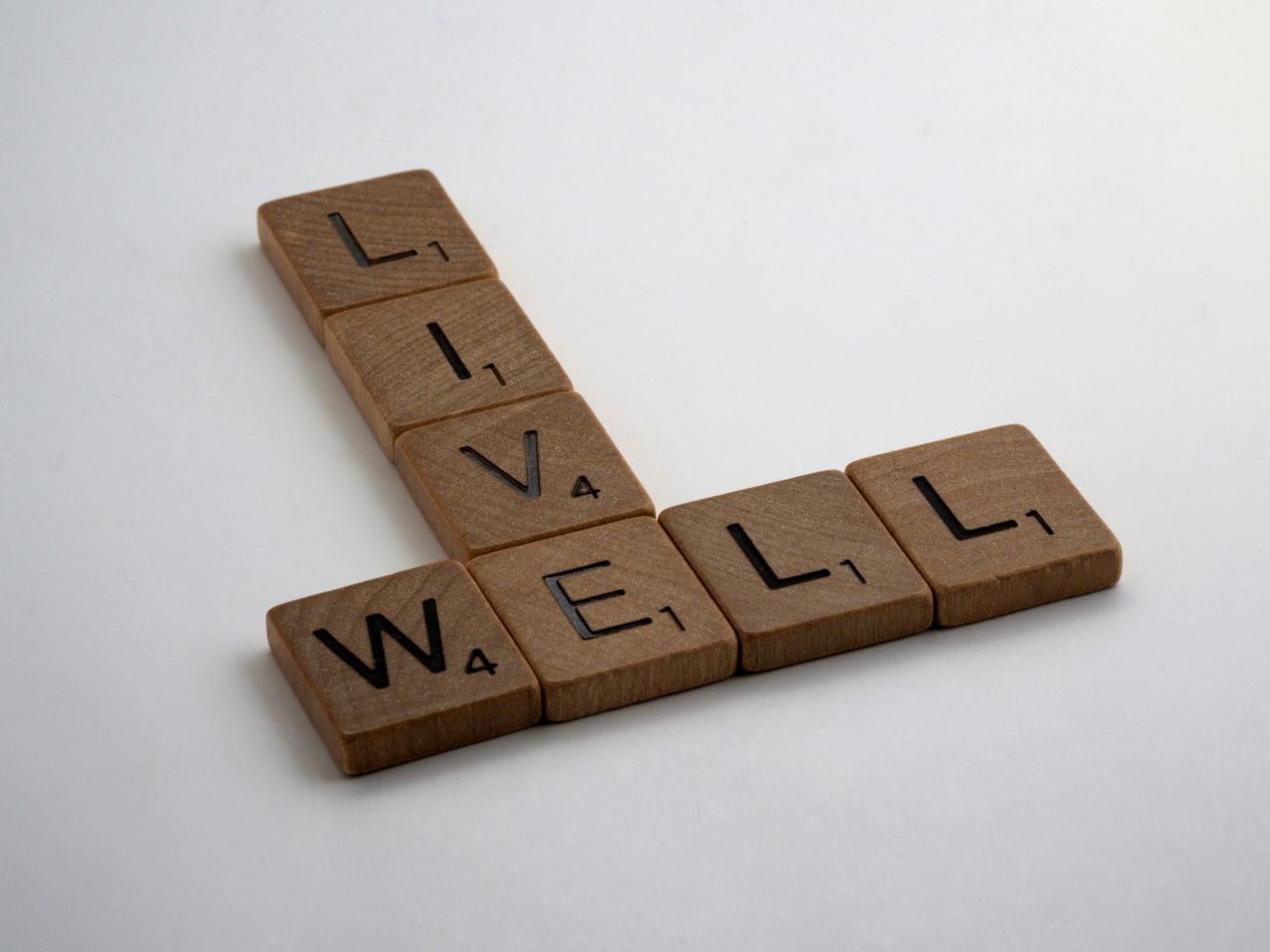 The Art of Drawing Readers In: Your attractive post title goes here Wooden Scrabble tiles spelling 'Live Well' on a white surface. Perfect for motivational content.